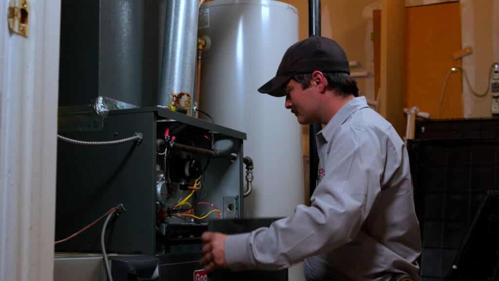 Technician performing a safety inspection on a high-efficiency residential gas furnace and boiler system.