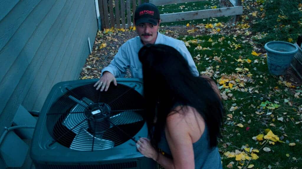 Licensed HVAC technician inspecting a residential air-conditioning unit for a seasonal tune-up.
